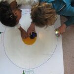 Kinder malen eine Umlaufbahn für Planeten auf Papier